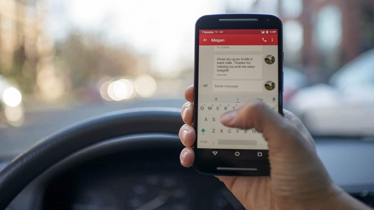 A driver holding a smartphone and typing a text message while driving, with one hand on the steering wheel.